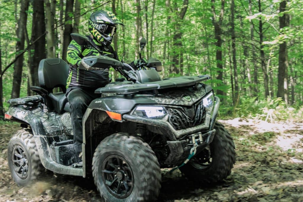 Dynamic shot of the CFMOTO CFORCE 600 Touring 2024 accelerating on a muddy trail.